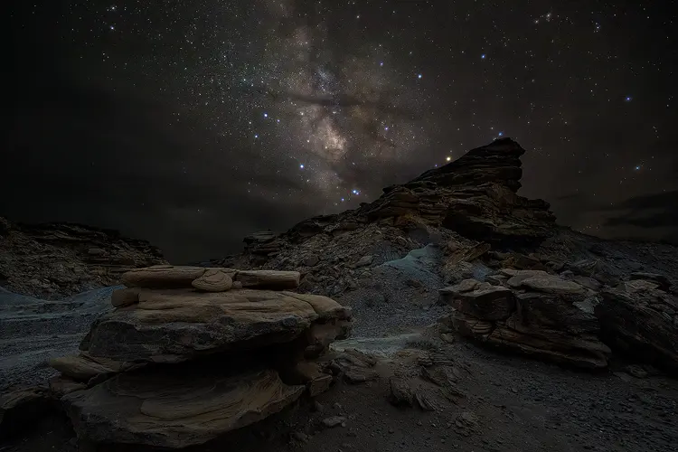 Workshop location; Large boulders are in the foreground of this image, but there are wide enough gaps between to see nicely past them to the rugged hillside behind. Above, the Milky Way sparkles in the night sky.