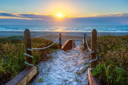 Path leading to stairs down to the beach at sunrise in Port Aransas, Texas.