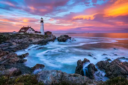 Sunset photo of the Portland Head Lighthouse on the Maine coast.