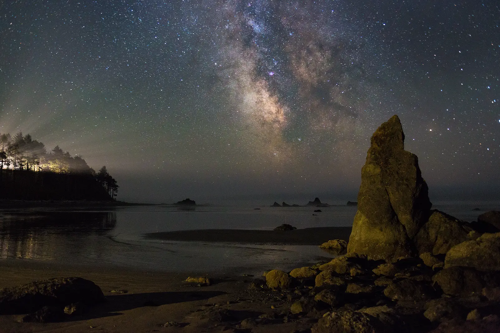Milky Way over Ruby Beach, Olympic National Park: rock spires, light beams through forest, Washington coast. Photo by Andy Cook.