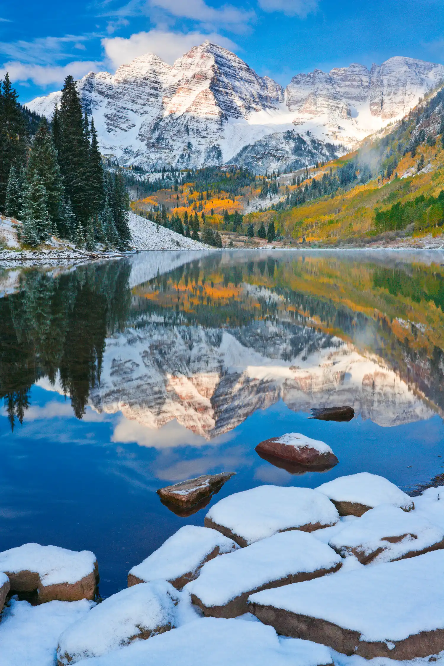 Maroon Bells and Maroon Lake at dawn with autumn snow and reflections.
