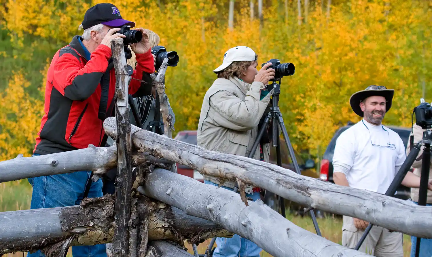 A group of photographers at an autumn workshop, one smiling at the camera.