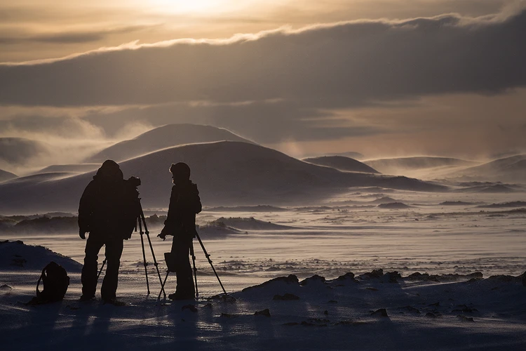 Photographers capturing a dramatic winter scene with blowing snow.