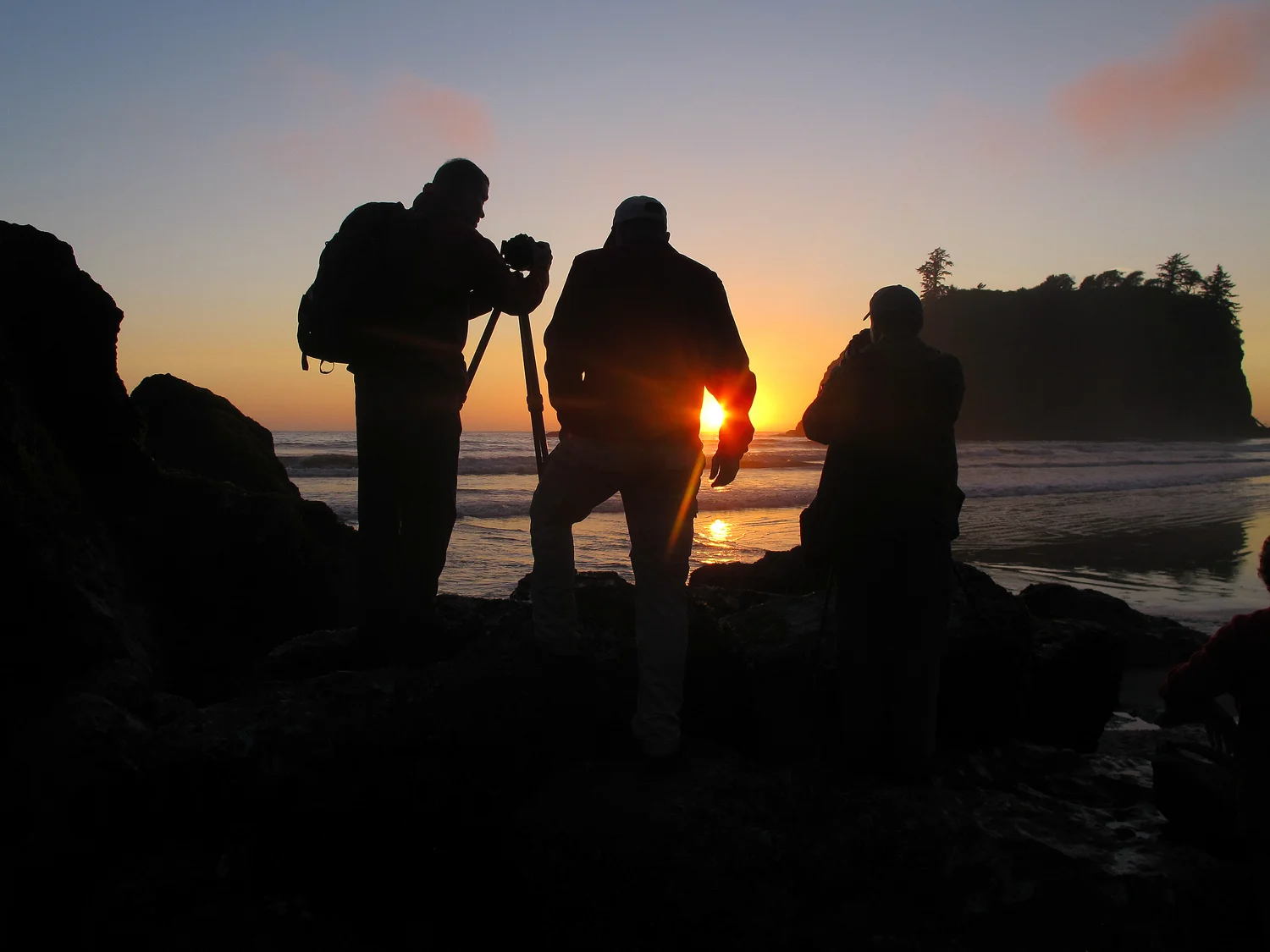A photography workshop group enjoying a sunset at the beach.