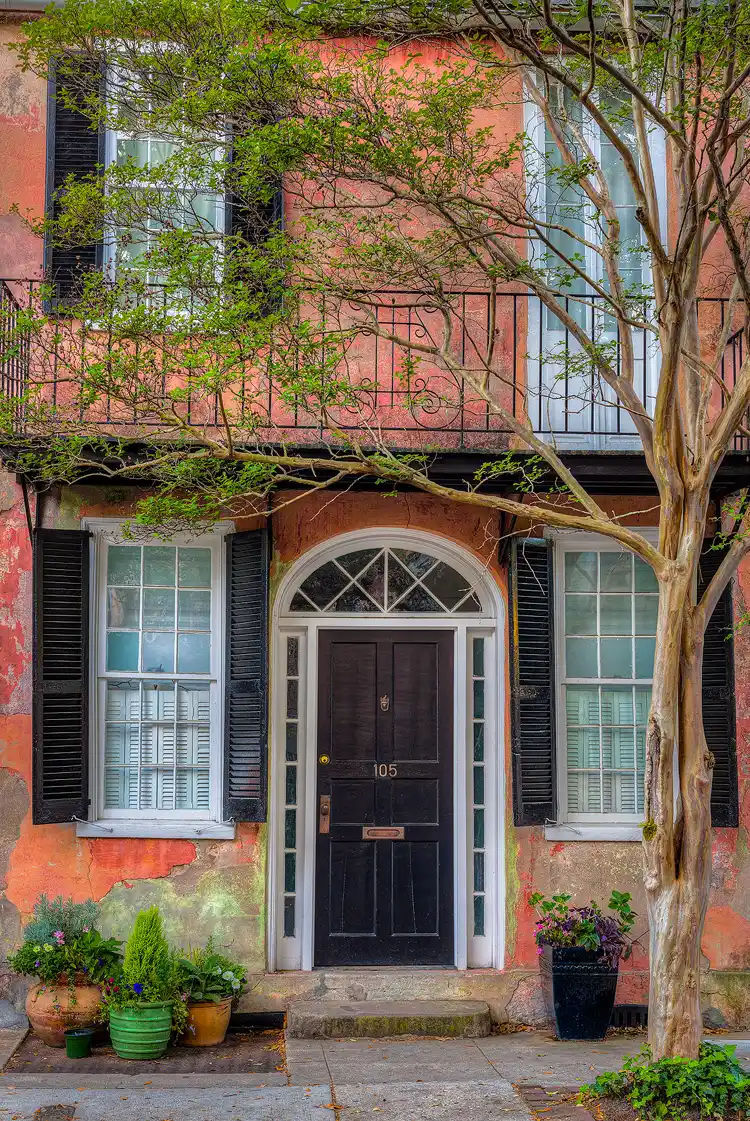 Historic Charleston home with orange stucco and spring foliage.