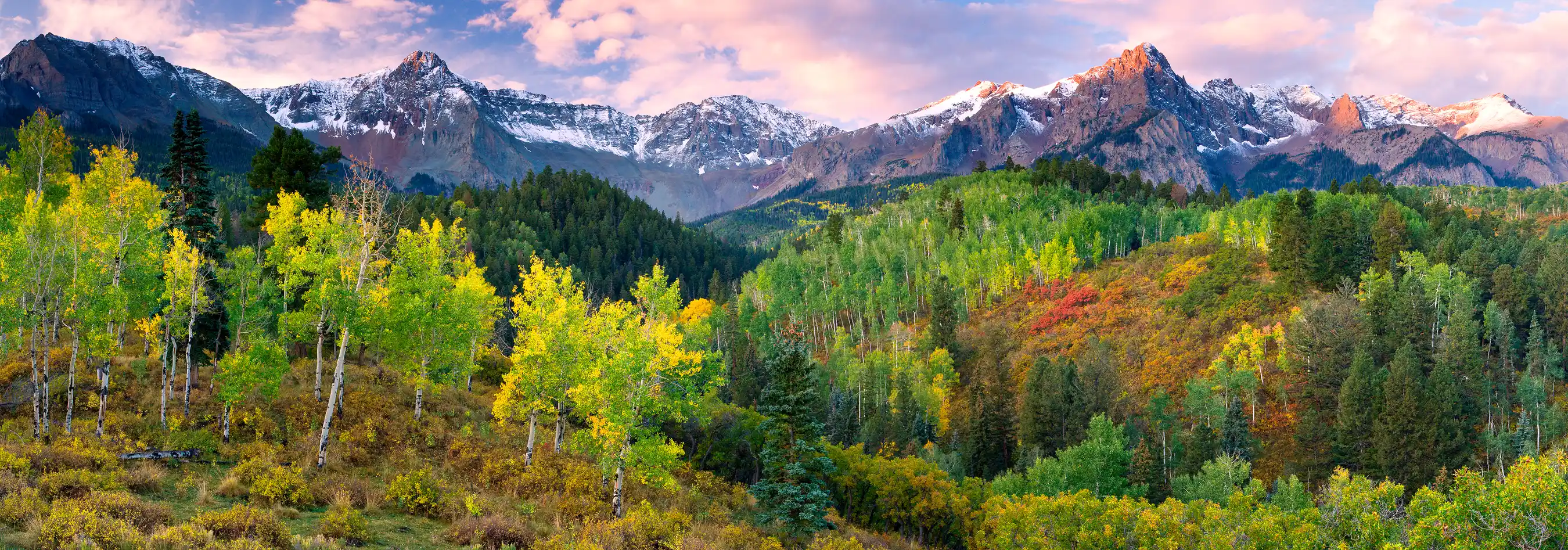 Stunning sunrise over the snow-capped San Juan Mountains and vibrant autumn foliage near Ridgway, Colorado.