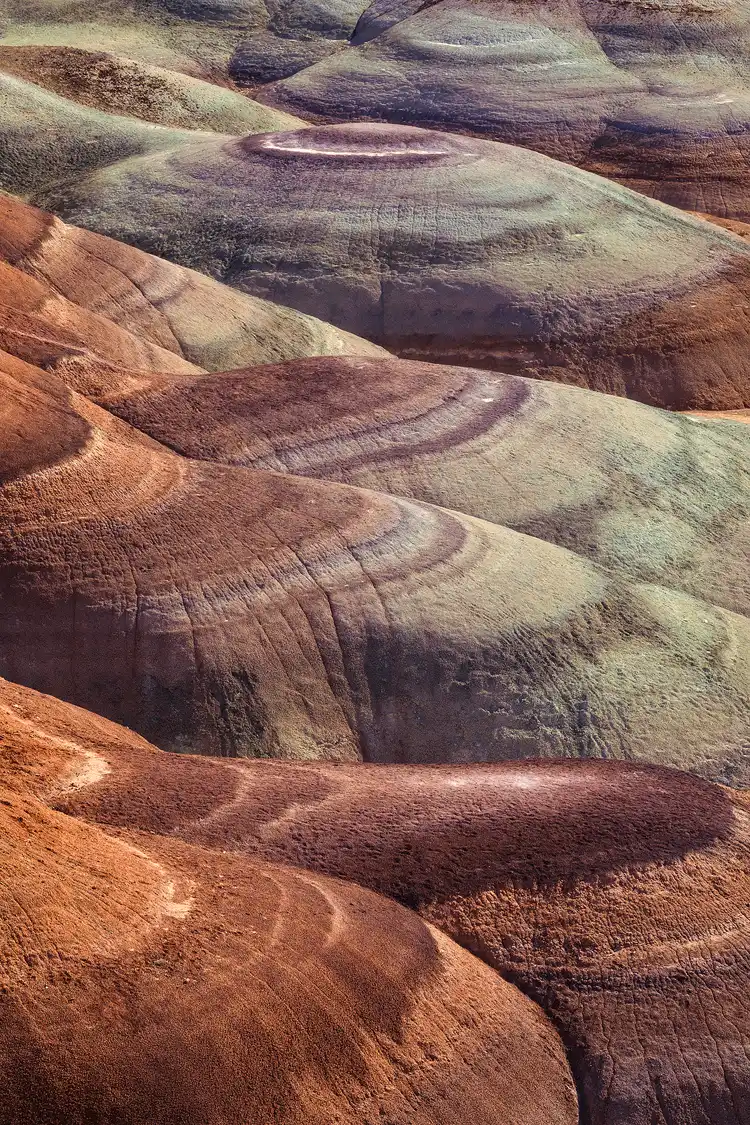 Colorful bentonite hills in Utah captured at morning, with vibrant layers and rounded formations filling the vertical frame.