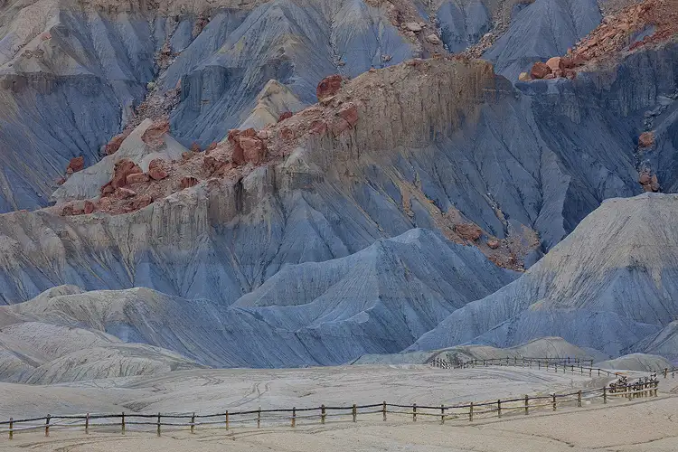 Shaded east side of North Caineville Mesa, Utah, with colorful layers and a leading wooden fence, as seen on our photography workshop.