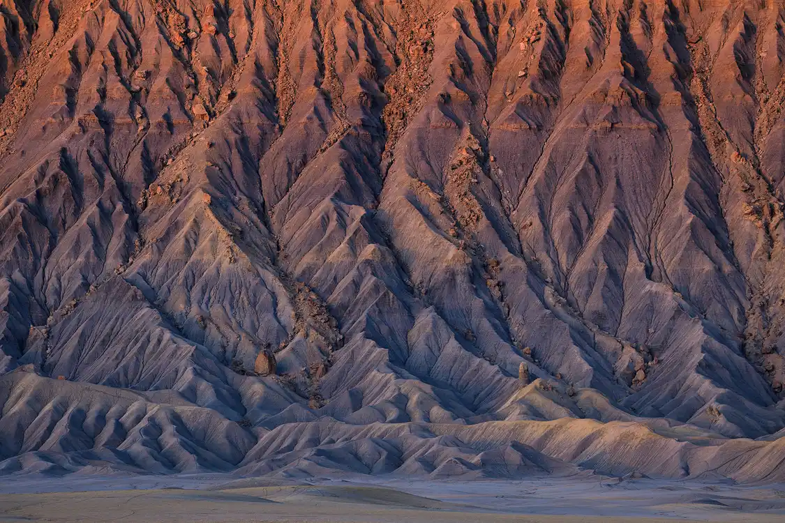 Sunrise light illuminating intricate drainage patterns on Factory Butte, Utah.
