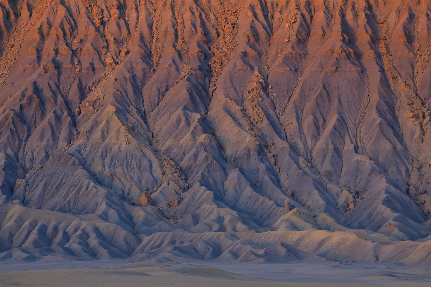 Sunrise light illuminating intricate drainage patterns on Factory Butte, Utah.