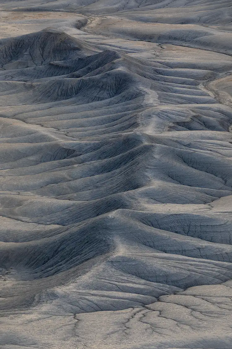 Monochromatic long shot of a curving ridge with ravine-carved slopes at Moonscape Overlook, Utah, resembling a backbone embedded in the desert terrain.