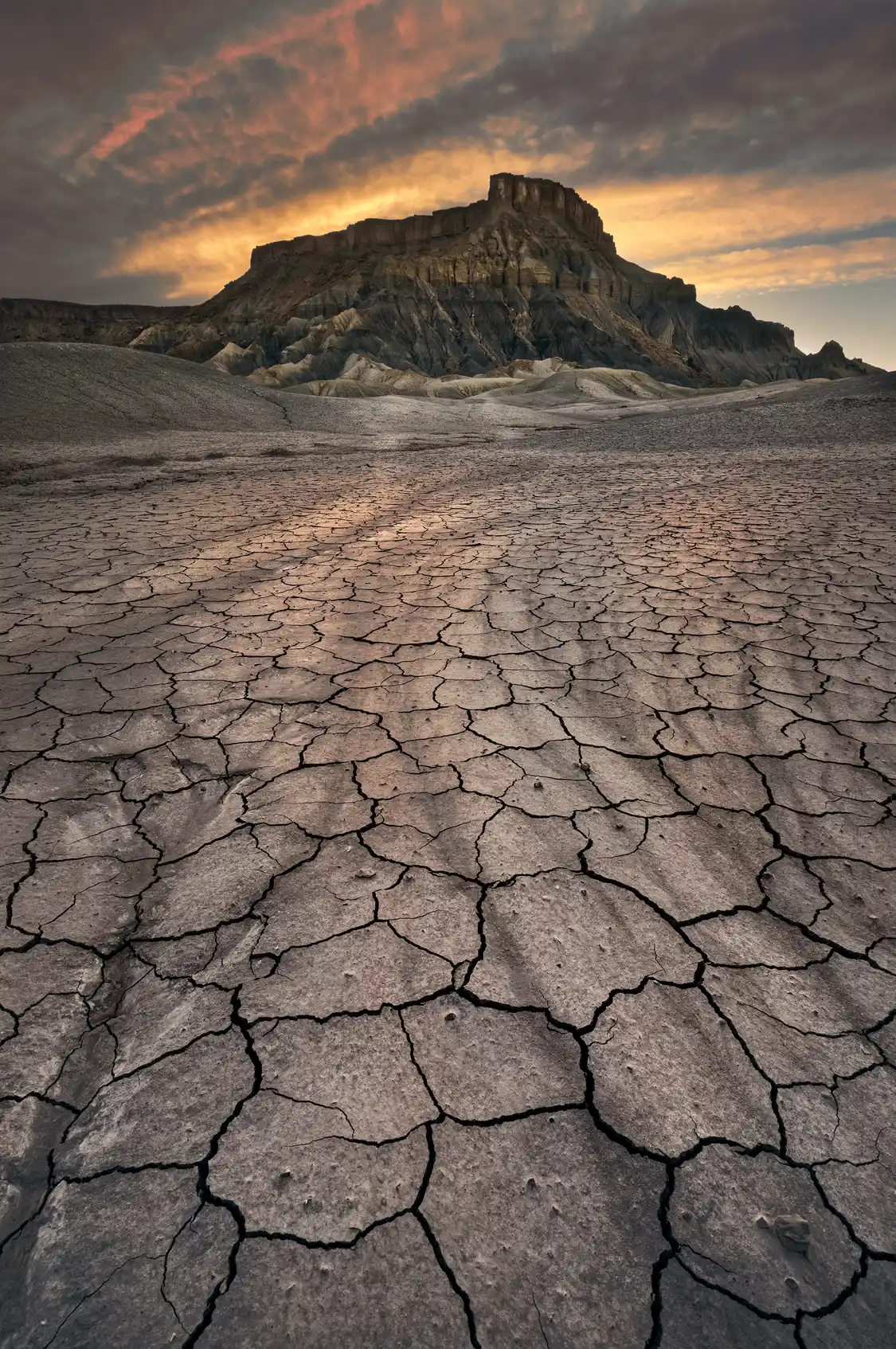 North Caineville Mesa at sunset above cracked desert mud near Hanksville, Utah.