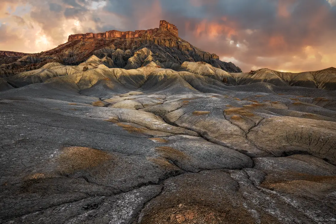 North Caineville Mesa above sculpted gray and ochre badlands at sunset in Utah.