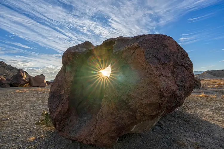 Sunstar shining through the opening in a volcanic boulder at Indian Head in Big Bend National Park.