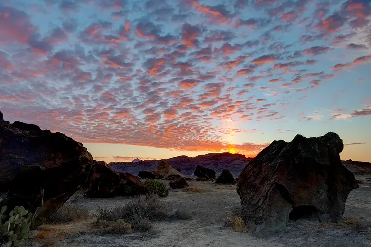 Colorful sunrise clouds above volcanic boulders at Indian Head in Big Bend National Park.