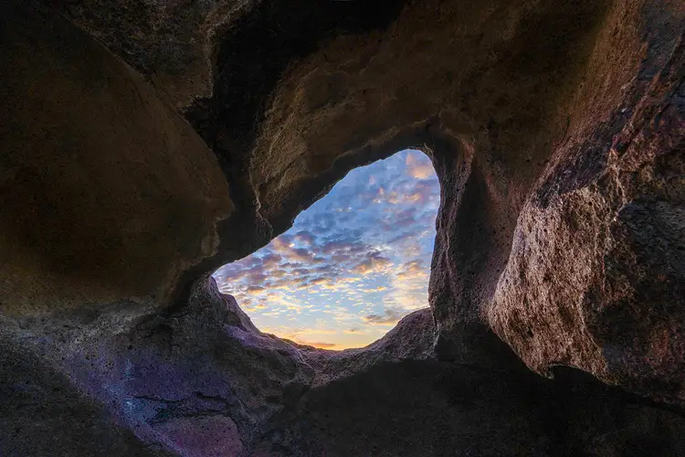 Sunrise clouds framed by a natural opening in volcanic rock at Indian Head in Big Bend National Park.