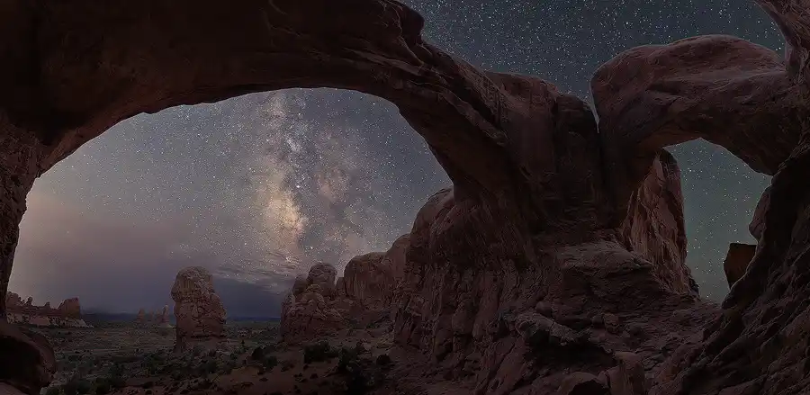 Milky Way framed by the sweeping opening of Double Arch in Arches National Park.