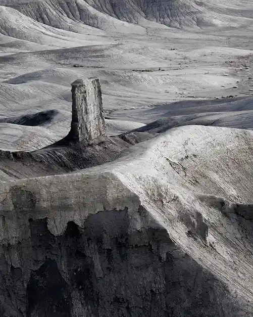 Solitary rock spire rising from smooth, eroded badlands at Moonscape Overlook near Hanksville, Utah.