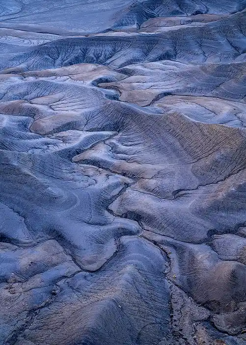 Pre-sunrise blue light revealing flowing ridges across the eroded badlands at Moonscape Overlook near Hanksville, Utah.