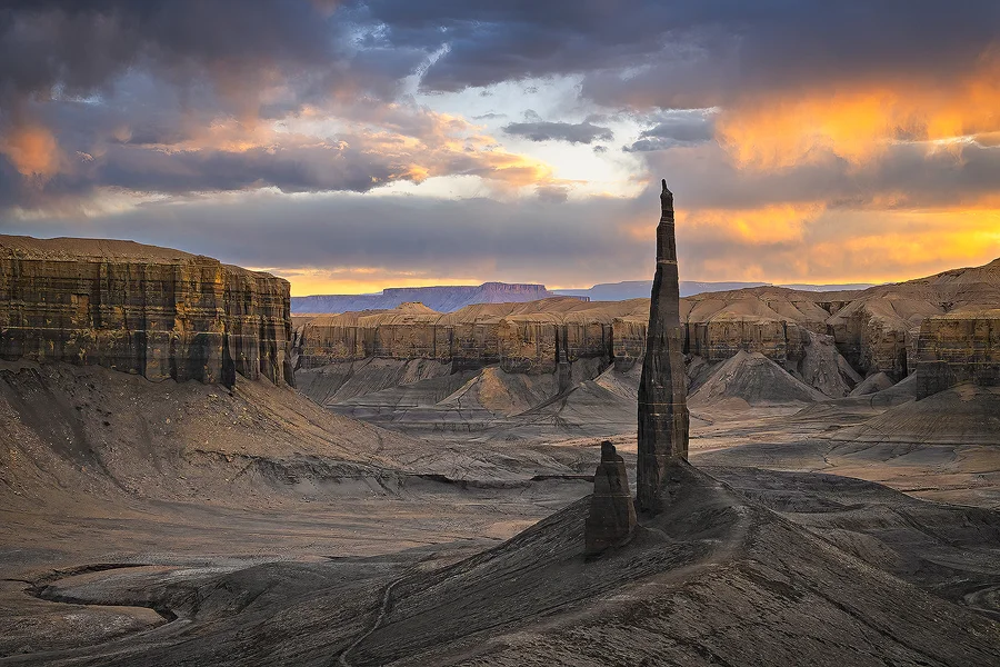 Long Dong Silver rising above the gray badlands beneath glowing sunset clouds near Hanksville, Utah.