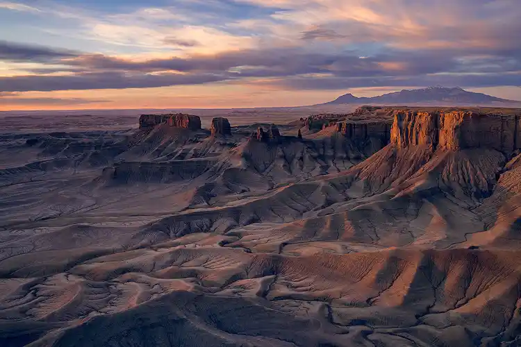 Morning light across the sculpted badlands at Moonscape Overlook with the Henry Mountains on the horizon near Hanksville, Utah.