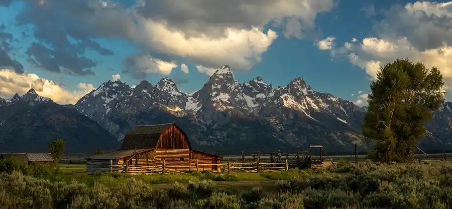 The historic John Moulton Barn beneath dramatic clouds and the Teton Range on Mormon Row, Grand Teton National Park.