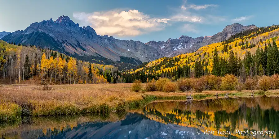 Golden aspens and the San Juan Mountains reflected in a still mountain pond during autumn in Colorado.