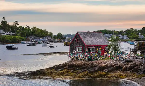Old lobster shack with buoys, Maine coast. Harbor view. Photo by Rick Thompson.