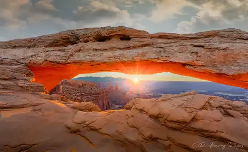 Sunrise at Mesa Arch, starburst, red glow under arch, Canyonlands. Photo by Chris Barry.