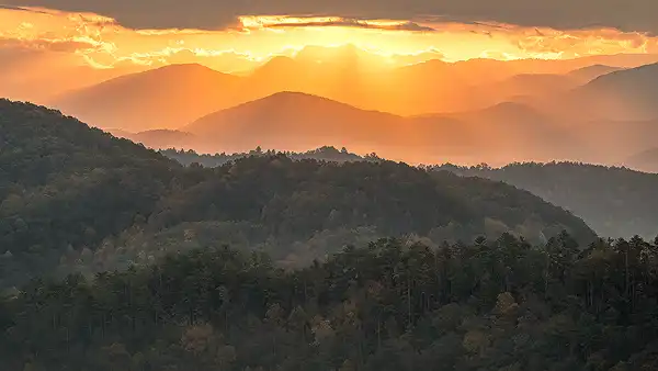 Sunrise rays over Smoky Mountains, layered mountains, fall. Long lens photo by Mark Leatherman.