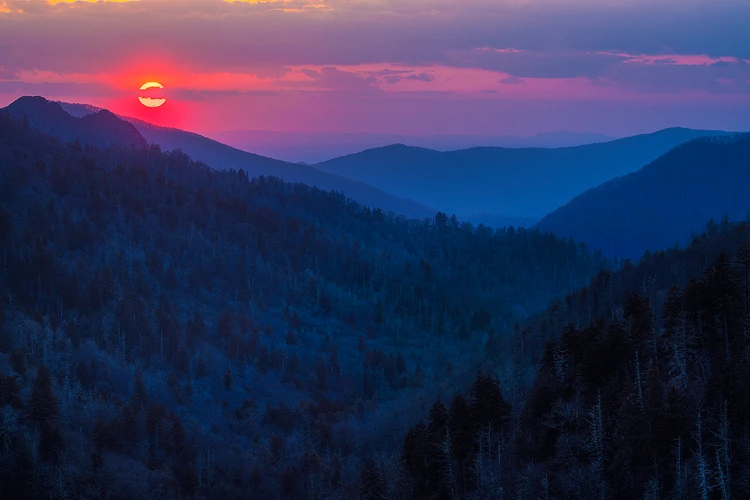 Workshop location; Layered, smoky blue mountains fade into the distance under a deep, red sky which glows around the setting sun. Great Smoky Mountains National Park.